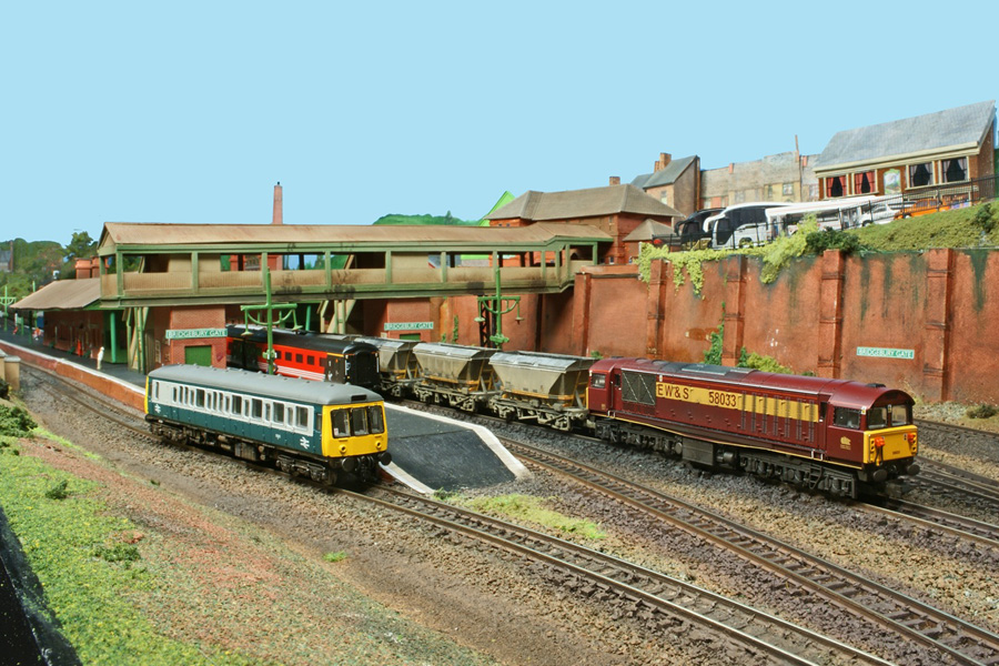 EWS-livery Class 58 No 58 033 rumbles through the station with a rake of covered hoppers.